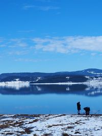 Men fishing while standing by lake during winter