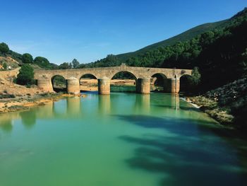 Arch bridge over river against sky