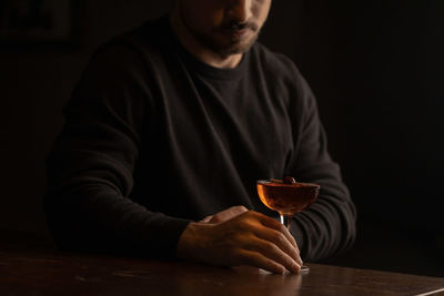 Midsection of man holding wineglass on table