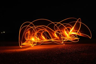 Illuminated light painting on field against sky at night