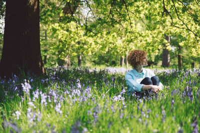 Woman sitting amidst plants at forest