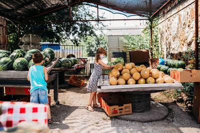 Two young kids shopping at local farmers market wearing face masks