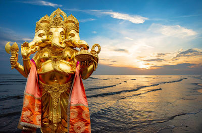 Statue by sea against sky during sunset