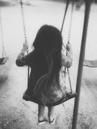 Rear view of girl sitting on swing at playground