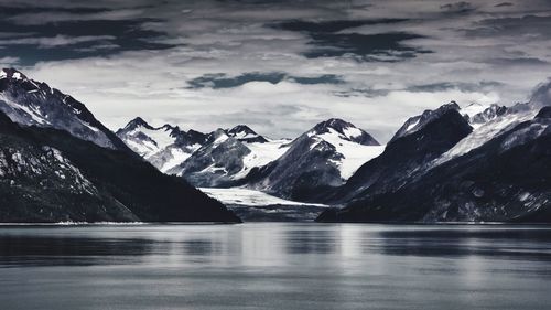 Scenic view of lake and mountains against cloudy sky