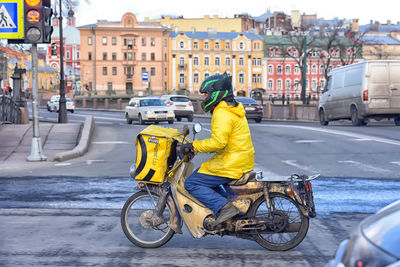 Rear view of man riding bicycle on city street