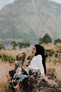 Side view of woman sitting on field