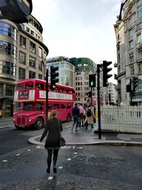 Full length of wet street by city against sky