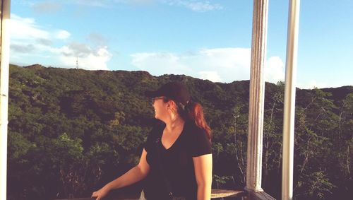 Woman standing by tree against sky