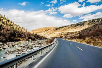 Diminishing perspective of empty road amidst mountains against sky