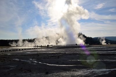 Panoramic view of people on landscape against cloudy sky