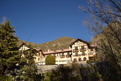 Low angle view of buildings and mountains against clear blue sky