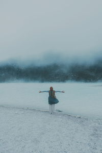 Man relaxing on snow covered land against sky