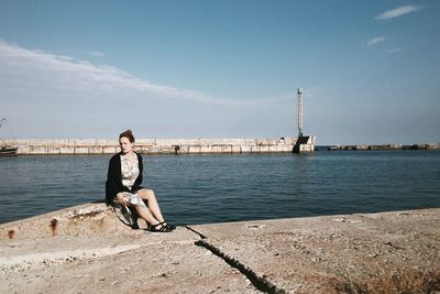 Full length of woman sitting at promenade against sky