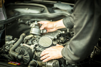 Midsection of man holding machine in car