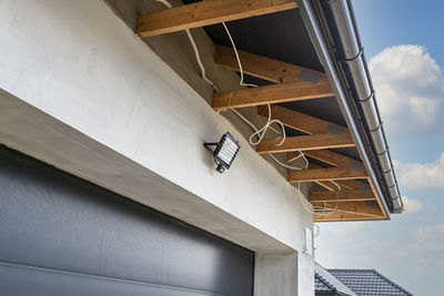 The light for the motion sensor mounted on the facade of the building above the garage door