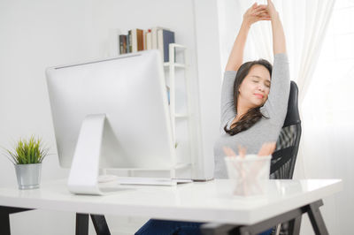 Young woman using phone while sitting on table