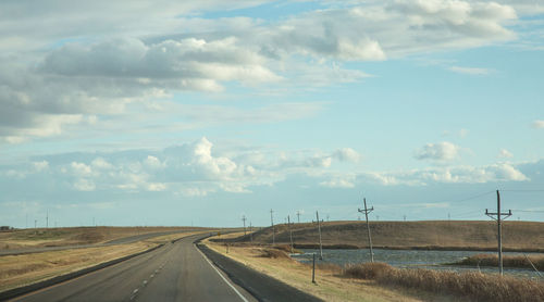 Road amidst field against sky