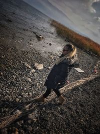 Woman standing at beach against sky