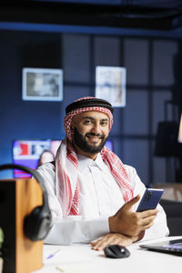 Portrait of young man using mobile phone in office