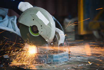 Manual worker using grinder at factory