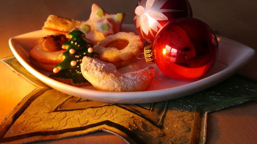 Close-up of christmas cookies and baubles in plate on table