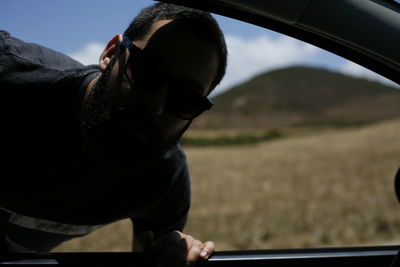 Close-up portrait of man looking through car window