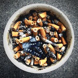 Directly above shot of cigarette butts in bowl on table