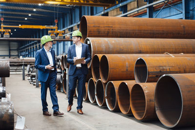 Male managing director discussing with coworker while walking in warehouse