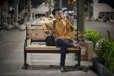 Portrait of young man sitting on bench