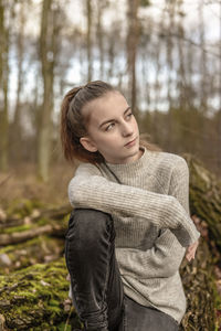 Thoughtful teenage girl sitting in forest