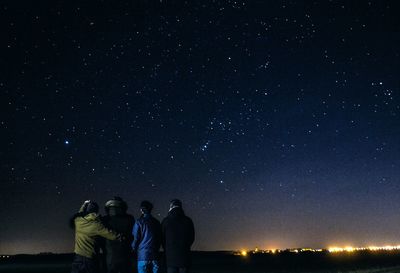 Rear view of people against star field at night