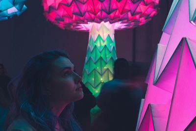 Portrait of woman looking at illuminated lighting equipment