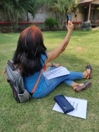 Rear view of woman using mobile phone in field