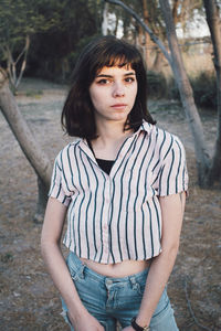 Portrait of teenage girl standing against tree