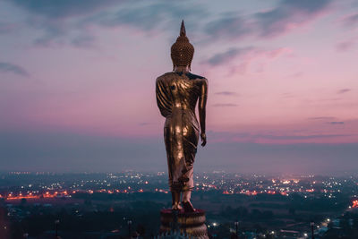 Statue of illuminated building against sky at sunset