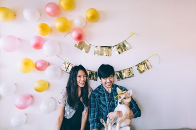 Smiling couple with dog against decorated wall