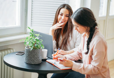 Businesswomen with laptop planning at desk in cafeteria