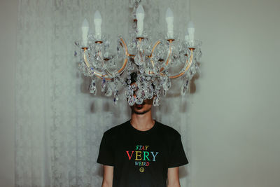 Teenage boy standing by chandelier at home
