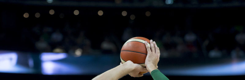 Cropped hands playing basketball in stadium