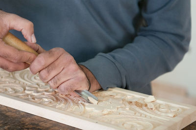 Midsection of man carving wood