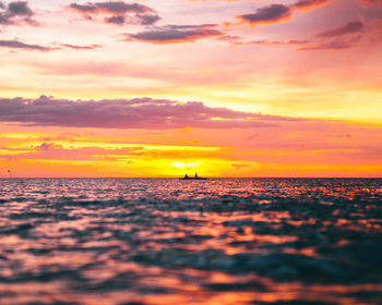 Scenic view of sea against dramatic sky during sunset