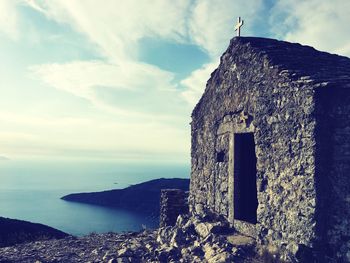 Old building by sea against sky