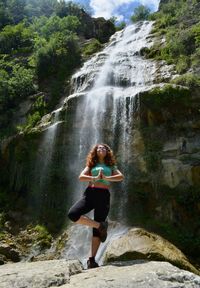 Full length of woman yoga by a waterfall