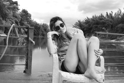 Woman sitting on railing against trees
