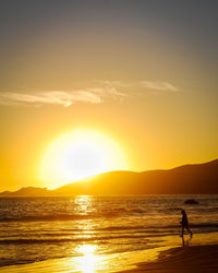 Silhouette man standing at beach during sunset