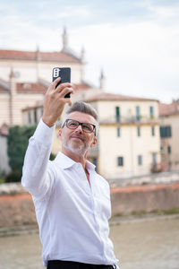 Businessman doing video conference call on smartphone and talking in the street, looking at screen