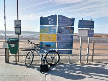 Bicycles on road by sea against sky