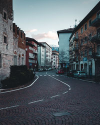 Empty road amidst buildings in city