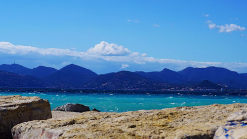 Scenic view of sea and mountains against blue sky